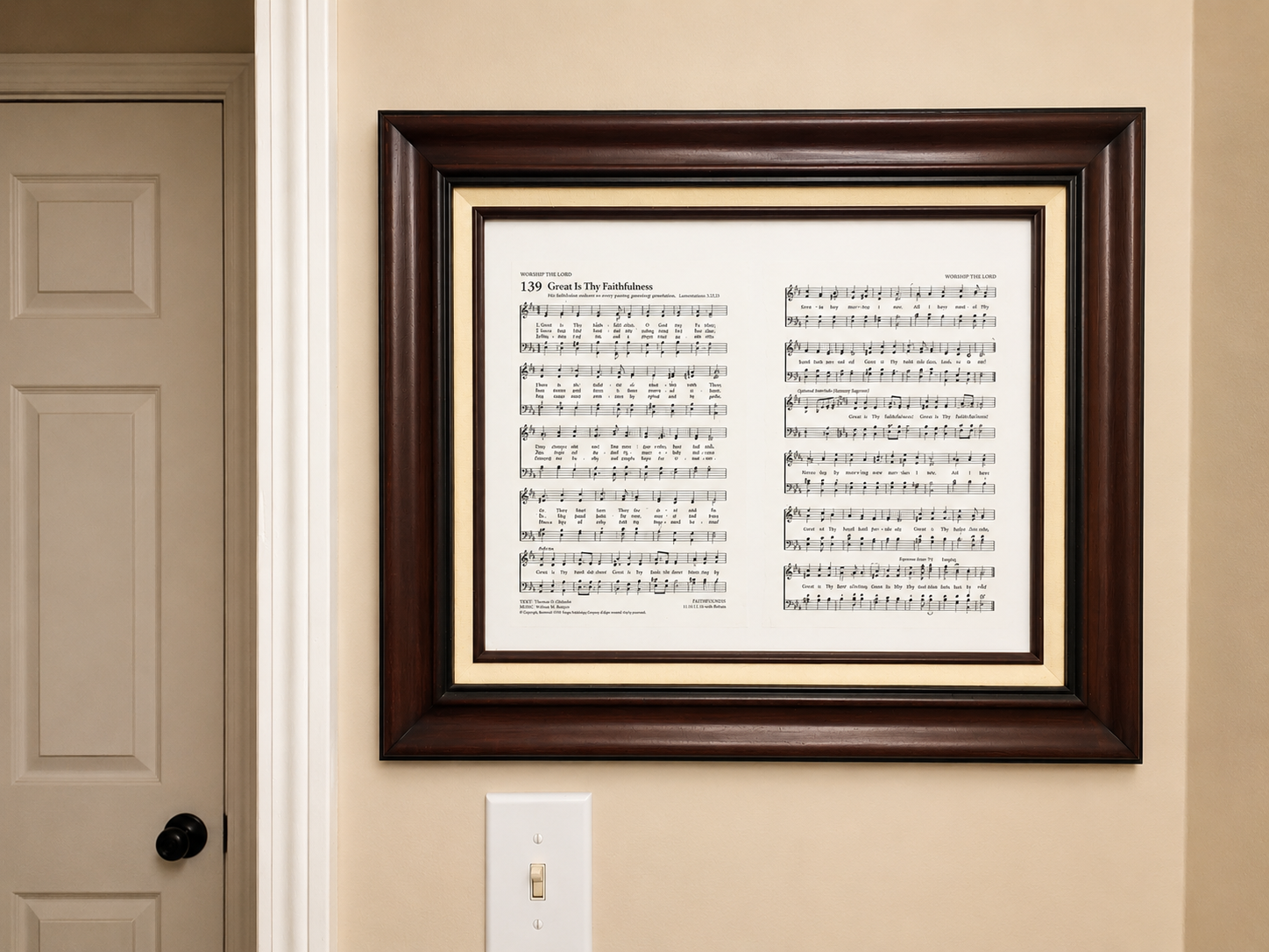 Framed Great Is Thy Faithfulness hymn sheet hanging on a cream wall beside a door