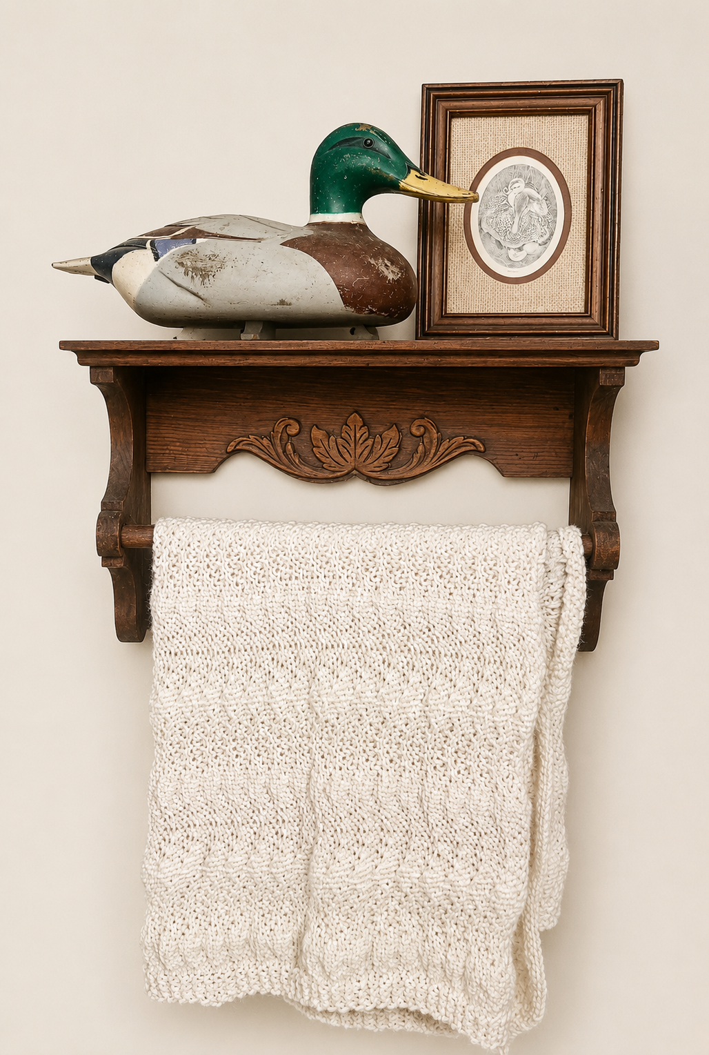 Carved wooden wall shelf with a mallard duck decoy, framed duck print, and a cream knit blanket draped below